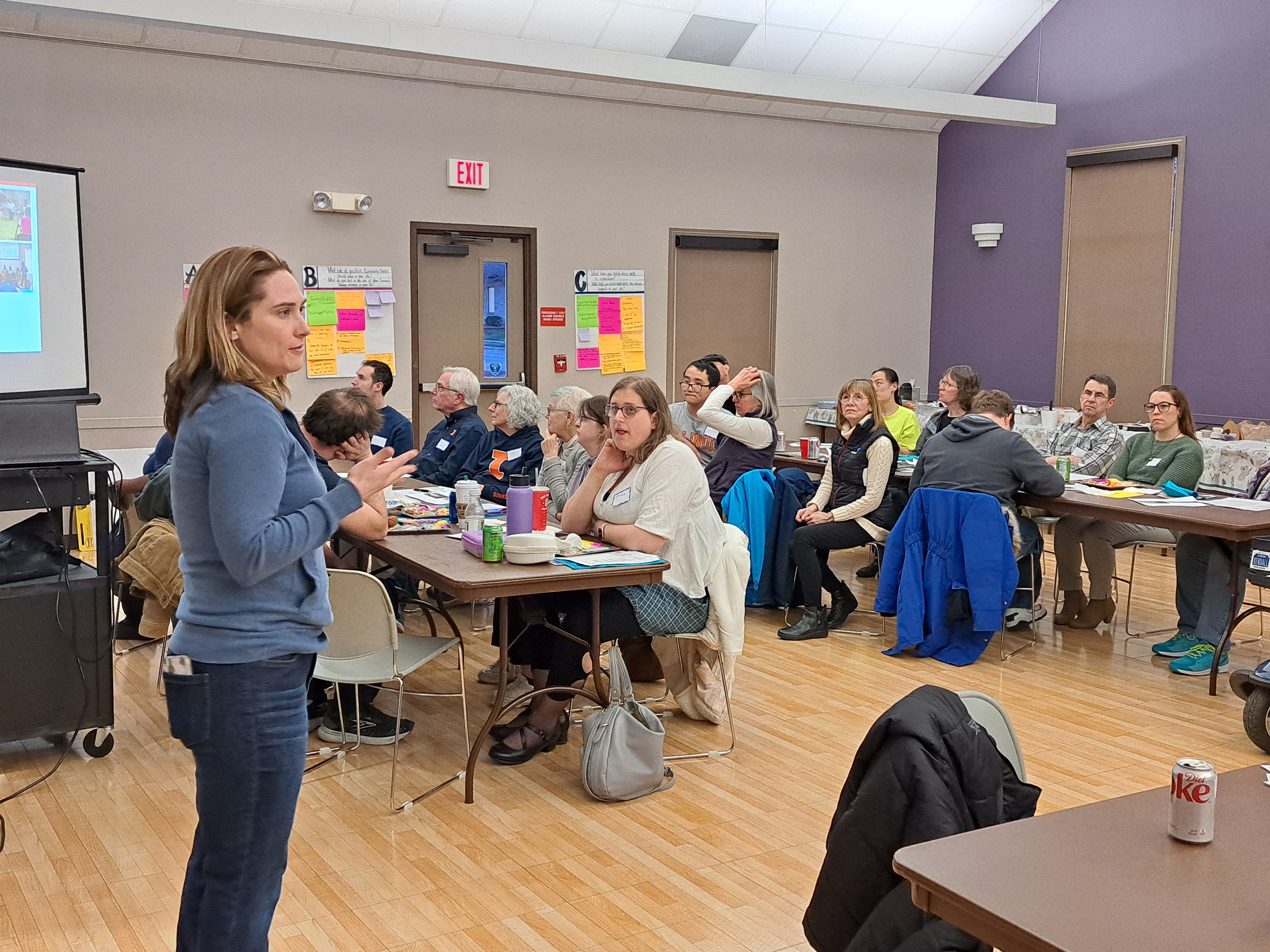 Heather Aldersey, the PI of this project, stands in front of a room of seated attendees, introducing the Balancing Act project to them.