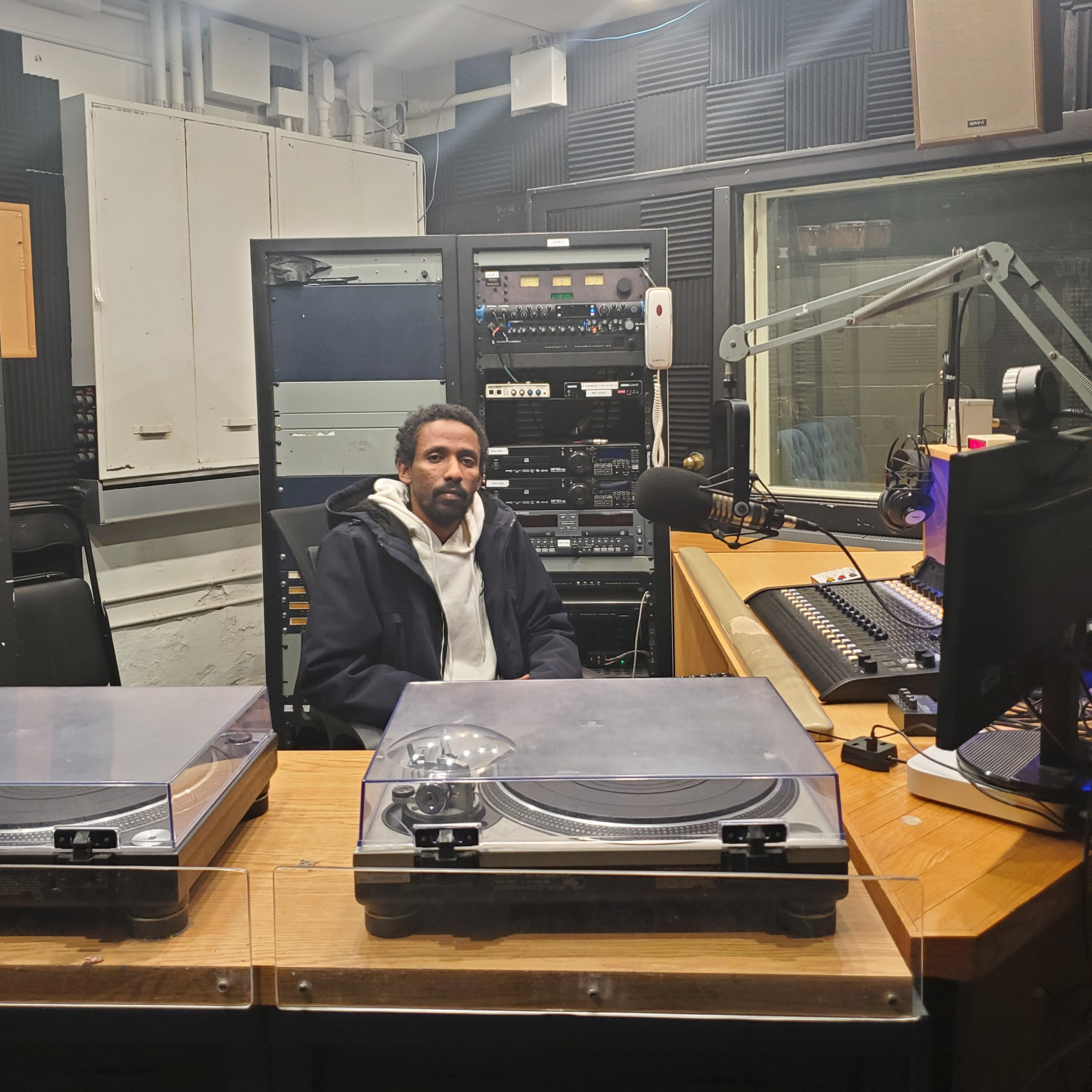 Getachew sits behind the desk at the radio studio where his podcast was recorded.