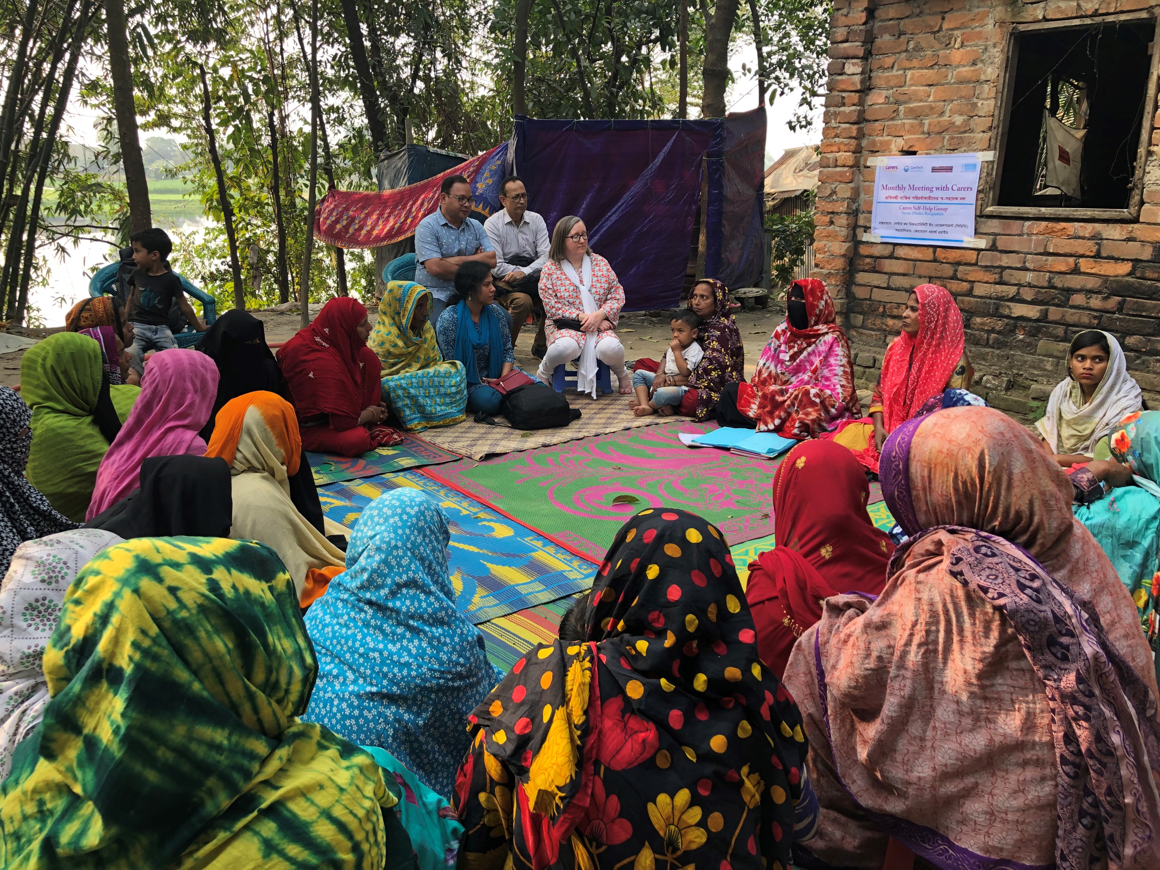 A group of women carers in Bangladesh sit together in a talking circle.
