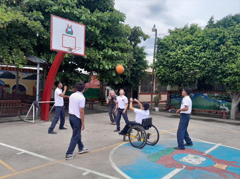 5 young men play basketball and 1 player in a wheelchair it taking a shot 