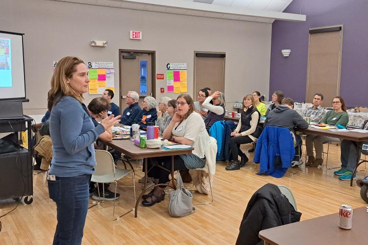 Heather Aldersey, the PI of this project, stands in front of a room of seated attendees, introducing the Balancing Act project to them.
