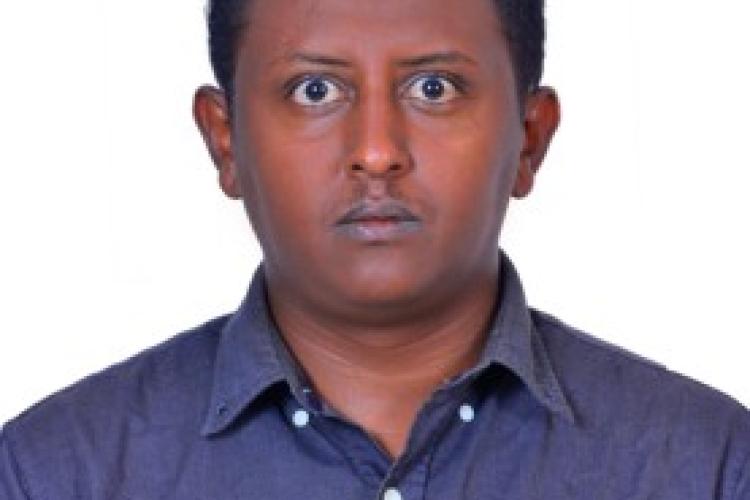 A headshot of Haben. He stares straight at the camera, wearing a blue shirt.