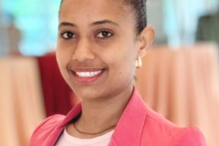Rediet poses, smiling, with a pink blazer and top.