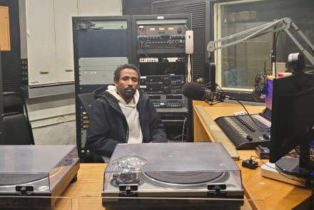 Getachew sits behind the desk at the radio studio where his podcast was recorded.