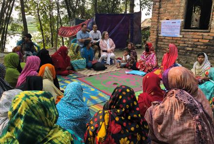 A group of women carers in Bangladesh sit together in a talking circle.