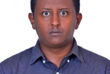 A headshot of Haben. He stares straight at the camera, wearing a blue shirt.