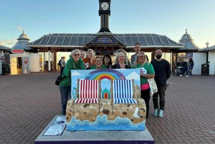 Amaze staff and parent carers pose with a bench.